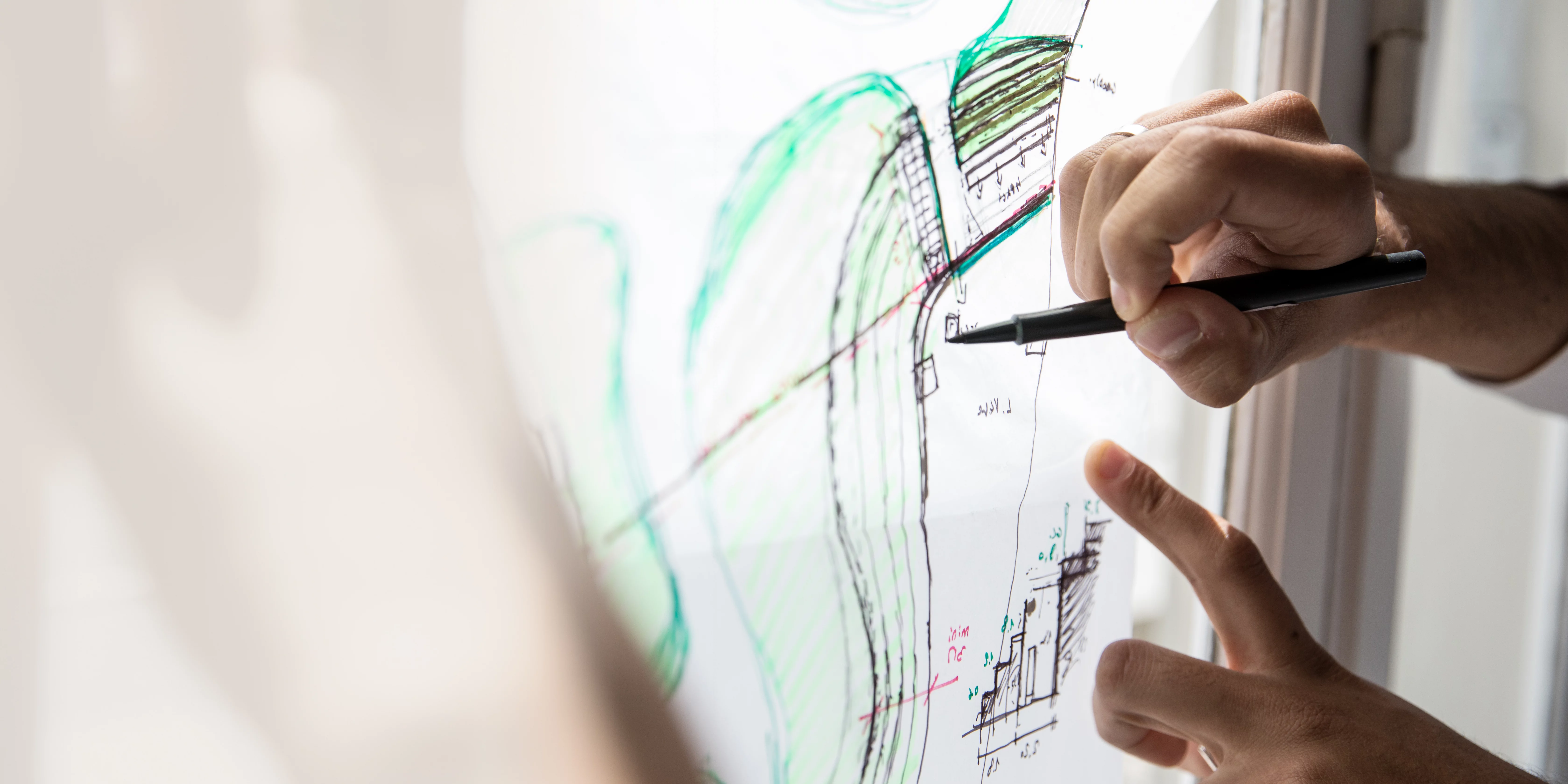 Making statements Hands are drawing precisely on a transparent plan that is mounted on a window