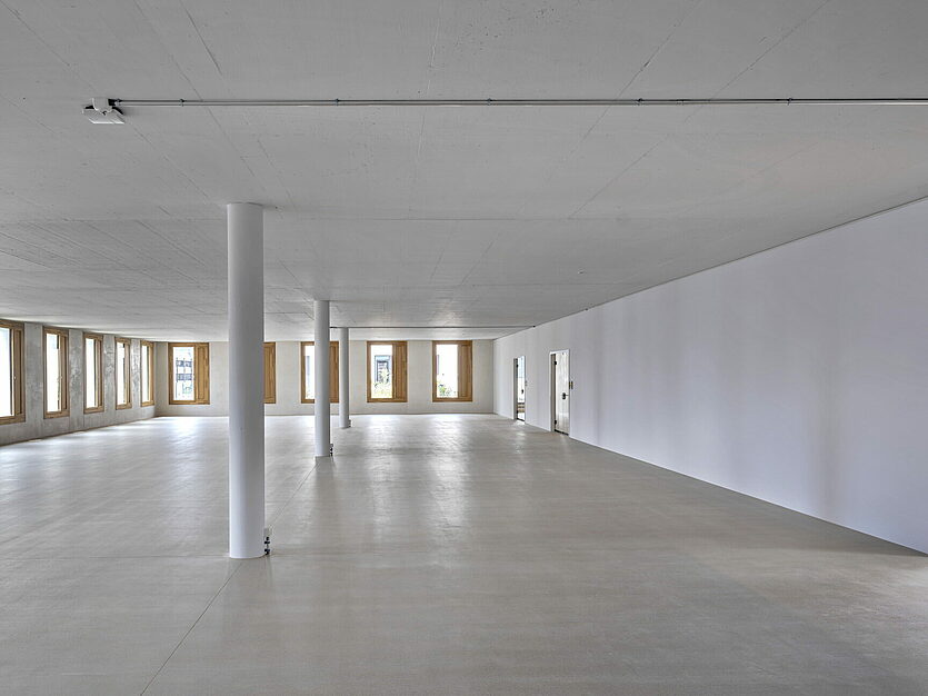 Lichtdurchfluteter Innenraum mit Fensterfront, Sichtbeton und runden Säulen