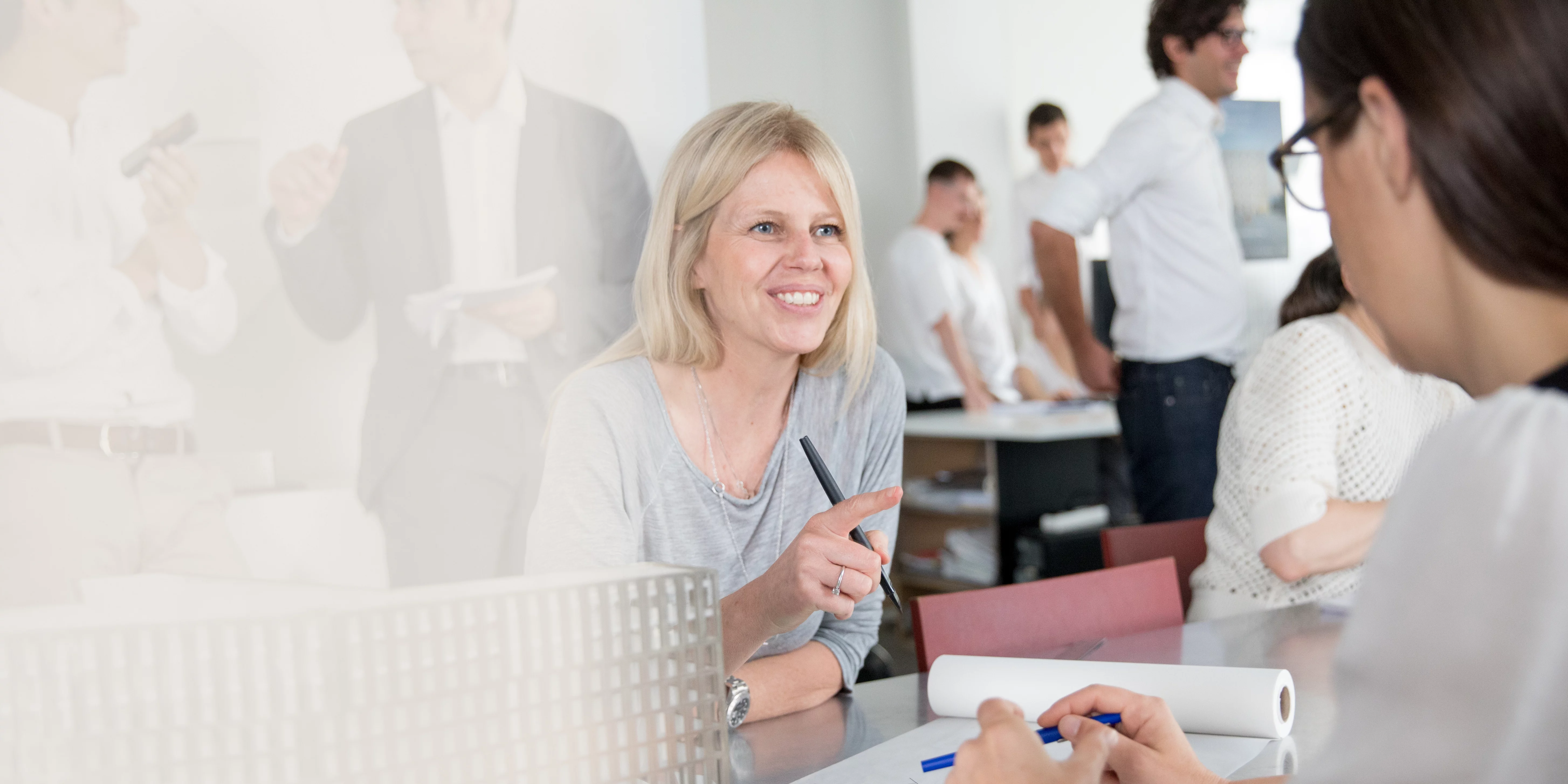 Telling stories Colleagues engage in a friendly conversation about architectural plans and models in the office