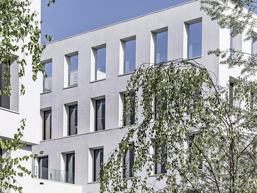 Moderne weisse Fassade des JED Schlieren mit schmalen Fenstern und Baum im Vordergrund