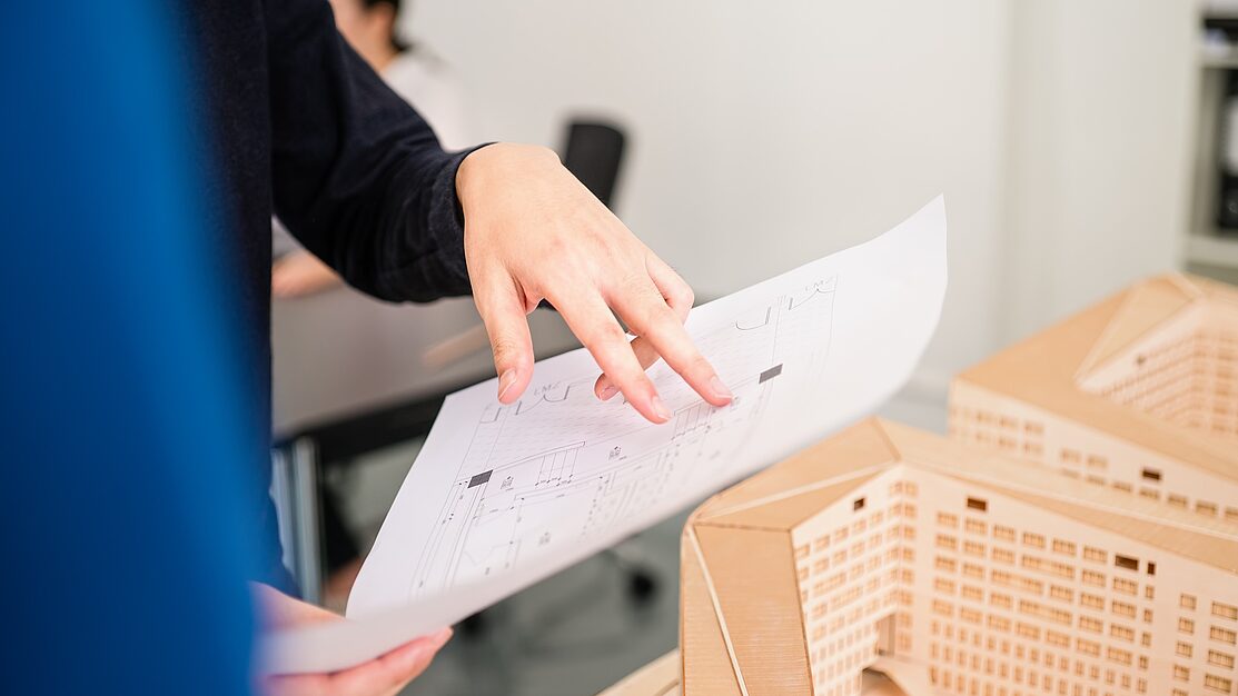 Architektin analysiert technische Zeichnungen im Planungsprozess eines neuen Projekts