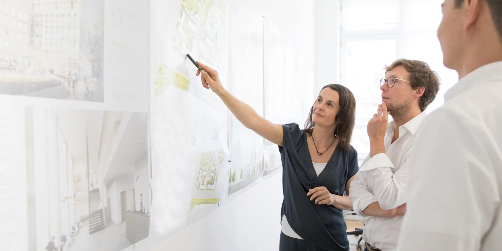 Taking responsibility An architect presents plans on a wall and discusses the project with colleagues