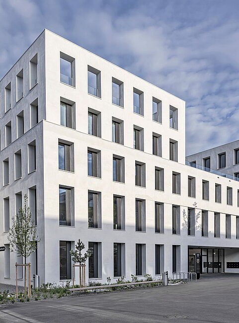JED Schlieren building with structured white façade and trees at the entrance area