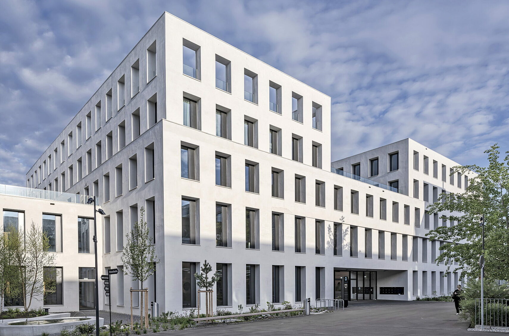 JED Schlieren building with structured white façade and trees at the entrance area
