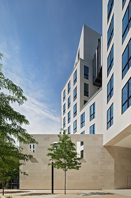 Neuinterpretation der Blockrandbebauung Helle, moderne Architektur mit kantigen Formen und großflächigen Fenstern unter blauem Himmel