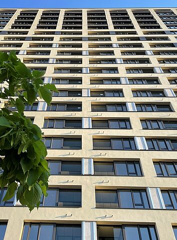 Fertigstellung Blick von unten auf ein hohes Wohn- oder Bürogebäude mit regelmäßigem Fassadenraster