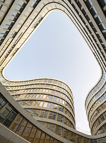 Auszeichnung Innenhof mit geschwungenen Fassadenlinien und Blick in den hellen Himmel