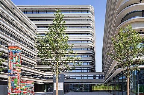 Edel-Rohbau für kreative Mieter Moderne Bürogebäude mit geschwungenen Fassaden und offenem Innenhof mit Bäumen