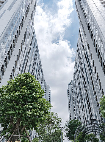 Auszeichnung Zwei moderne Hochhäuser mit Innenhof und gepflegter Bepflanzung bei blauem Himmel